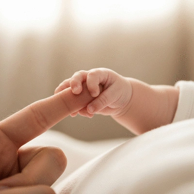 Close-up of a baby's hand gently grasping a parent's finger, symbolizing the comfort and security provided by a reliable baby monitor. The background is softly blurred in a nursery setting.